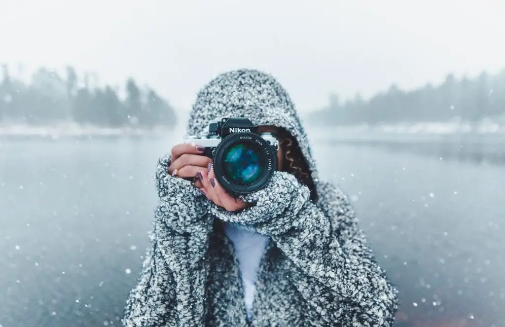 woman holding a camera in an snowy scene