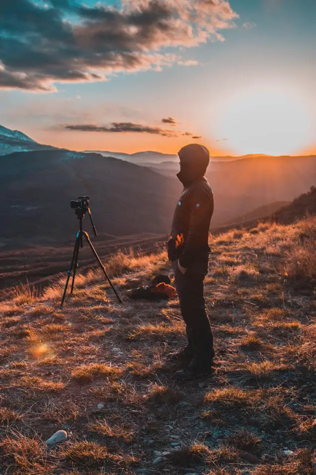 Photographer preparing his camera for night photography in a mountain setting.