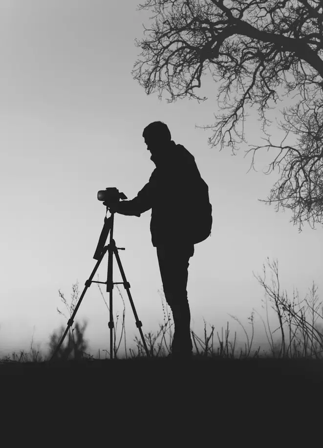 silhouette photo of a man holding a tripod