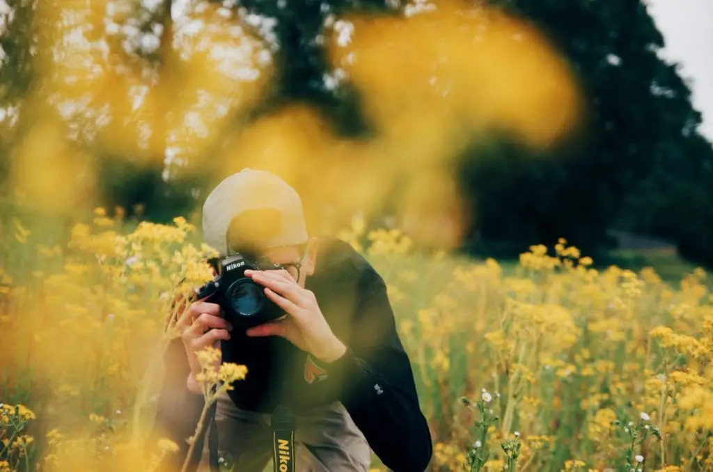 Photographer taking his camera to photograph flowers in a large garden