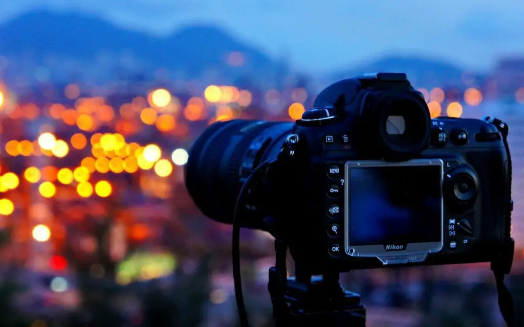 Nikon camera is set up in front of a view of a city lights.