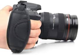 person holding a black camera in a white surface background