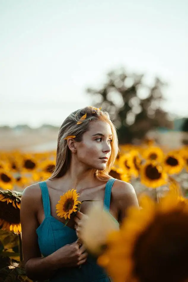 a girl with blue shirt holding sunflower