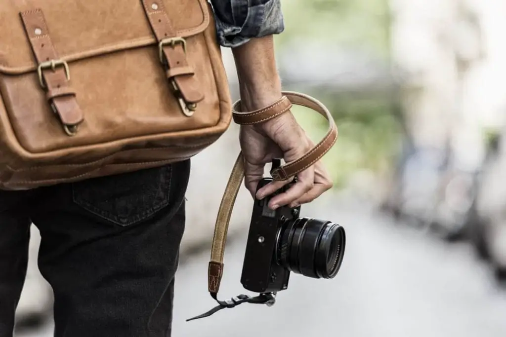 Man with a leather sling bag holding a camera