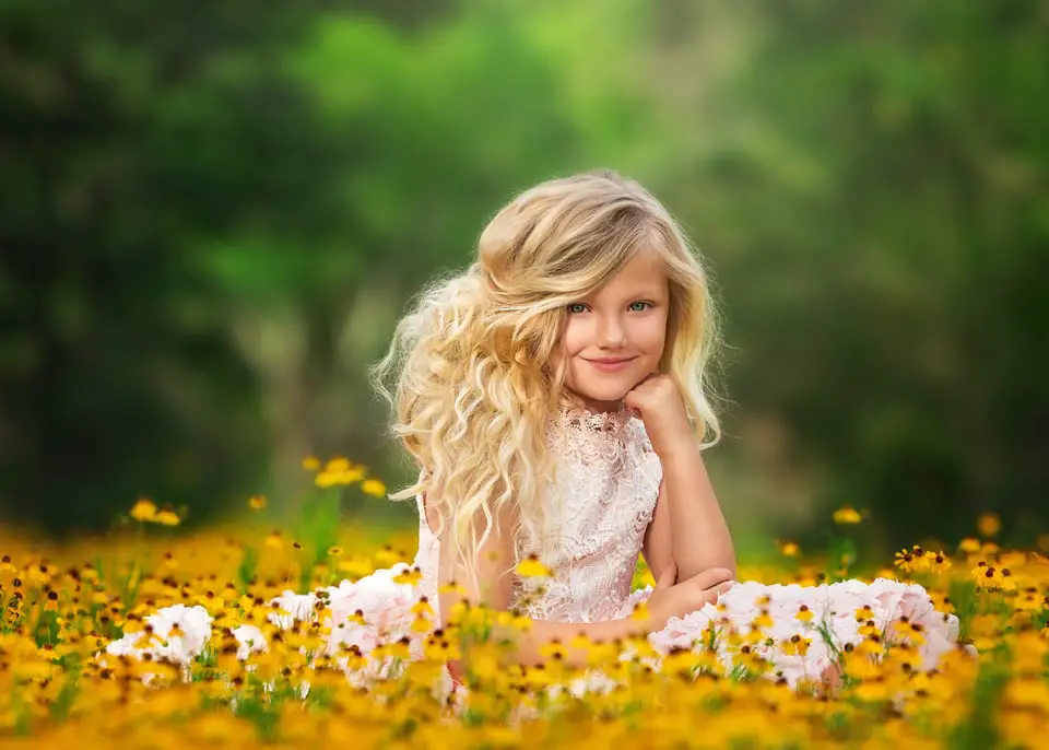 blonde girl in white gown in a yellow flower garden