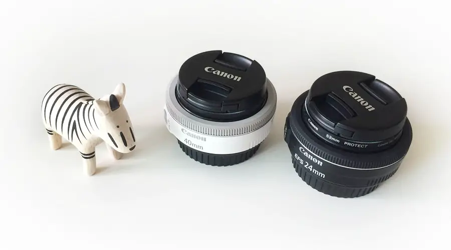 two camera lens with a zebra toy on a white surface