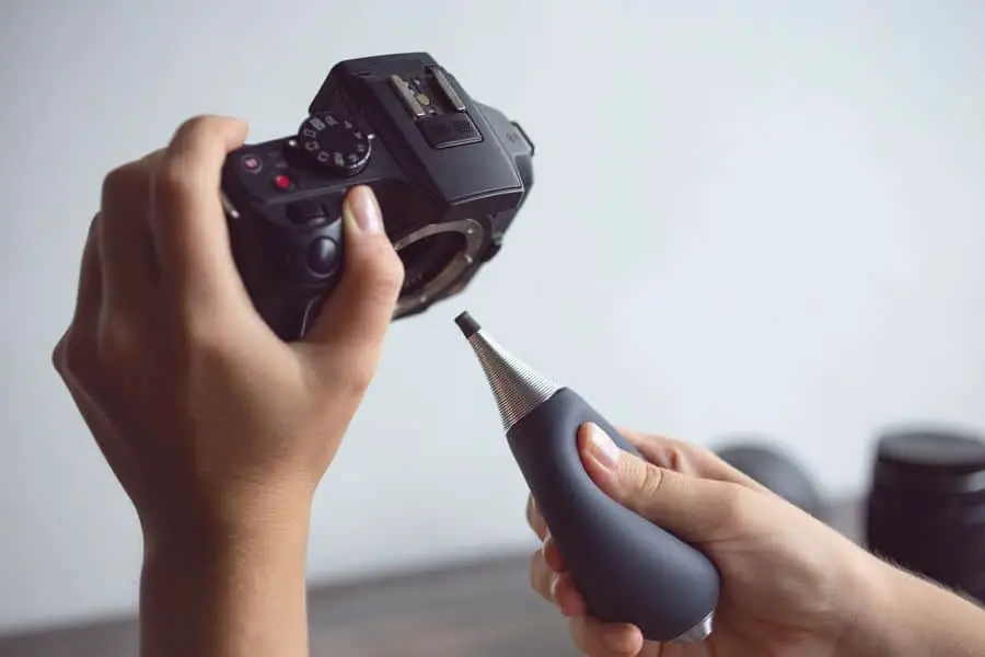 Person using a blower to clean a DSLR sensor