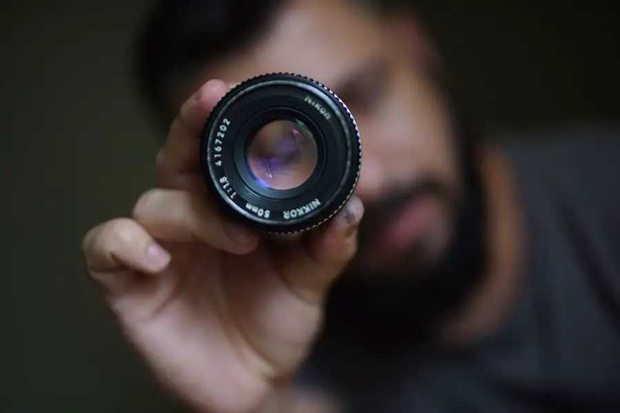Man holding a Nikon 50mm f/1.8 lens