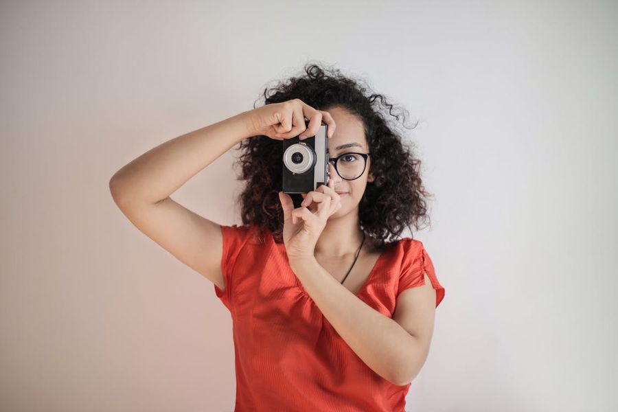 Woman wearing glasses trying to take a photo of a subject
