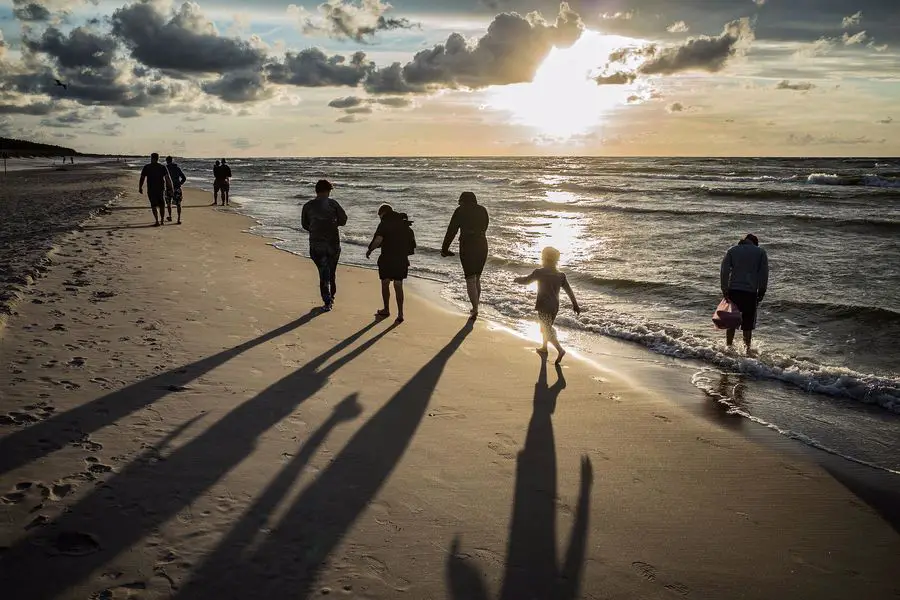 Photo of a family walking on a beach with visible shadows