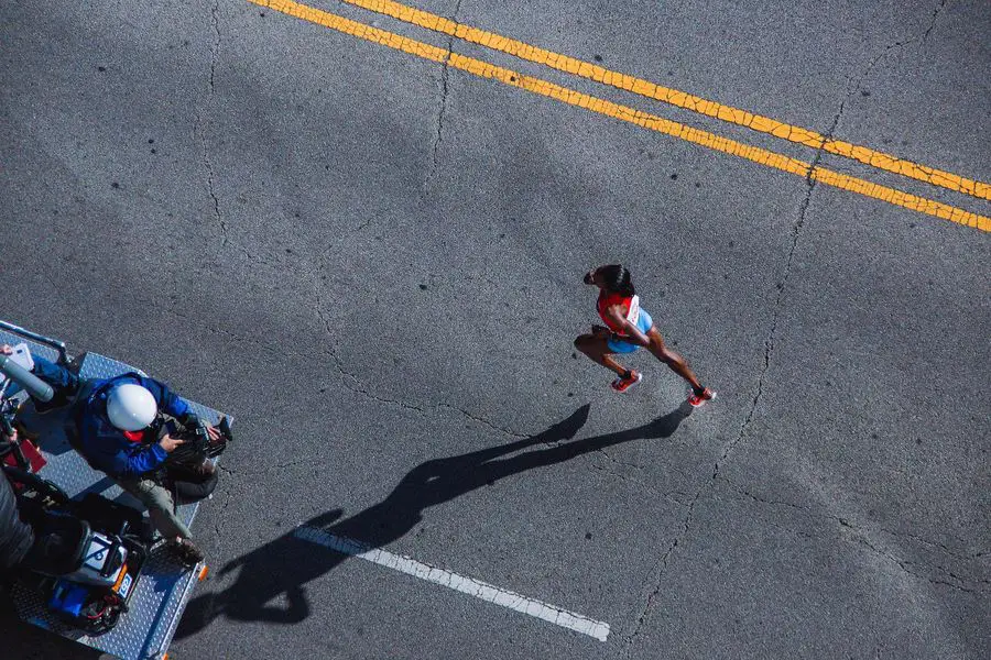 Man taking photos of a woman running in a pavement